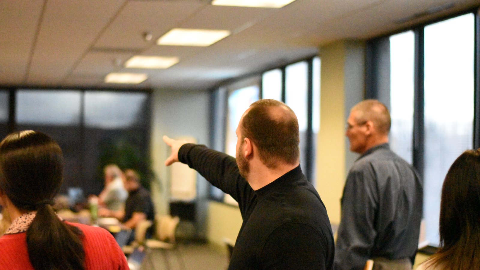 Josh Aragon working a room during a live session, pointing across the table mid-discussion.